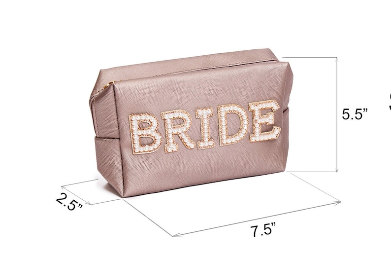 May include: A light pink satin cosmetic bag with the word "BRIDE" spelled out in gold letters with pearl accents. The bag measures 7.5 inches wide, 5.5 inches tall, and 2.5 inches deep.