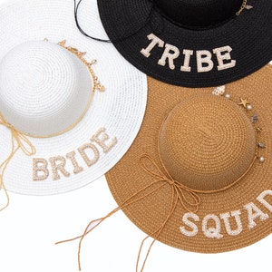 May include: Three straw hats with different colored bands and embellishments. The hats are labeled "Bride", "Tribe", and "Squad".