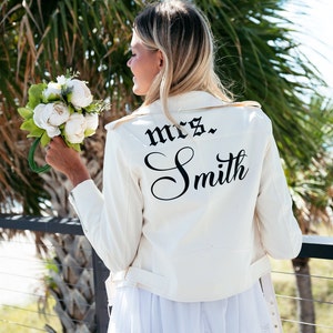 K&ouml;nnte beinhalten: Eine wei&szlig;e Lederjacke mit einer schwarzen Aufschrift auf dem R&uuml;cken, die "mrs. Smith" lautet.