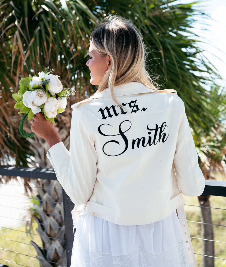 K&ouml;nnte beinhalten: Eine wei&szlig;e Lederjacke mit einer schwarzen Aufschrift auf dem R&uuml;cken, die "mrs. Smith" lautet.