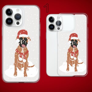 Puede incluir: Dos fundas para tel&eacute;fono con fondo blanco y un dise&ntilde;o de un perro boxer con un gorro de Pap&aacute; Noel y una bufanda roja en una escena nevada. El texto "1" es visible en la esquina superior derecha de la imagen.