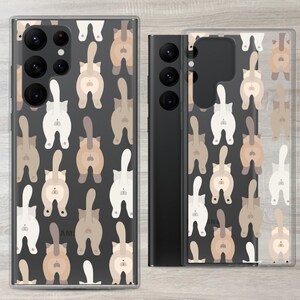 May include: A clear phone case with a black background and a pattern of brown, white and tan cats with their tails up in the air. The cats are facing away from the viewer.