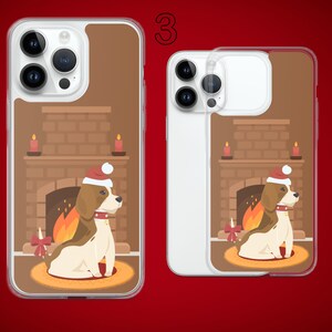 Puede incluir: Una funda transparente para tel&eacute;fono con un dise&ntilde;o navide&ntilde;o. La funda presenta un perro beagle con un gorro de Pap&aacute; Noel sentado frente a una chimenea con fuego encendido. El texto "3" es visible en la esquina superior derecha de la imagen.