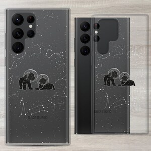 Może przedstawiać: Przezroczyste etui na telefon z czarnym wzorem galaktyki i sylwetką psa i kota w hełmach astronaut&oacute;w. Etui jest przeznaczone do telefonu Samsung.