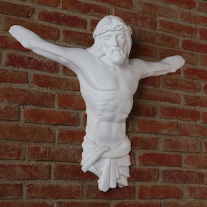 May include: A white sculpture of Jesus Christ on a red brick wall. The figure has outstretched arms, a crown of thorns, and a draped cloth. The sculpture is a religious decorative item.