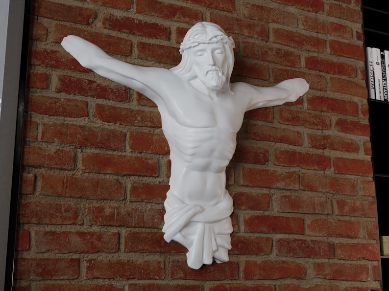 May include: A white sculpture of Jesus Christ on a red brick wall. The figure has outstretched arms, a crown of thorns, and a draped cloth. The sculpture is a religious decorative item.