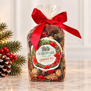 May include: A clear plastic bag filled with potpourri, featuring dried pinecones, red berries, and foliage. A bright red satin ribbon is tied at the top. The label reads: COUNTRYSIDE Fragrances CHRISTMAS PINE NET WT. 4 OZ./113 G. with a wreath graphic.