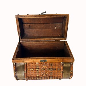 May include: Open wooden chest with a hinged lid. The chest features a woven rattan front with brass accents and a metal clasp. The interior is a dark brown color. The chest is empty and sits against a white background.