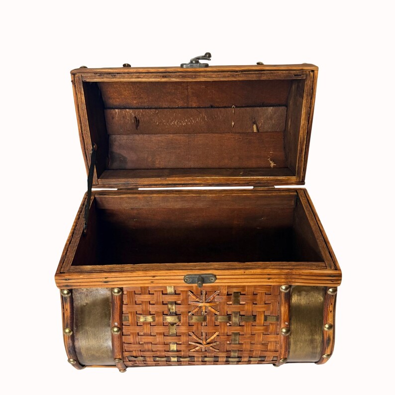 May include: Open wooden chest with a hinged lid. The chest features a woven rattan front with brass accents and a metal clasp. The interior is a dark brown color. The chest is empty and sits against a white background.