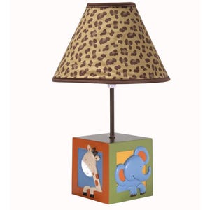 May include: A decorative table lamp with a brown and tan leopard print lampshade. The base is a cube with a giraffe and elephant design. The lamp is approximately 18 inches tall.