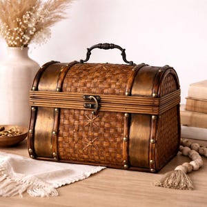 May include: A decorative brown chest with a woven design, metal accents, and a handle. The chest features a curved top and is secured with a latch. The chest is made of wood and metal and has a vintage aesthetic.