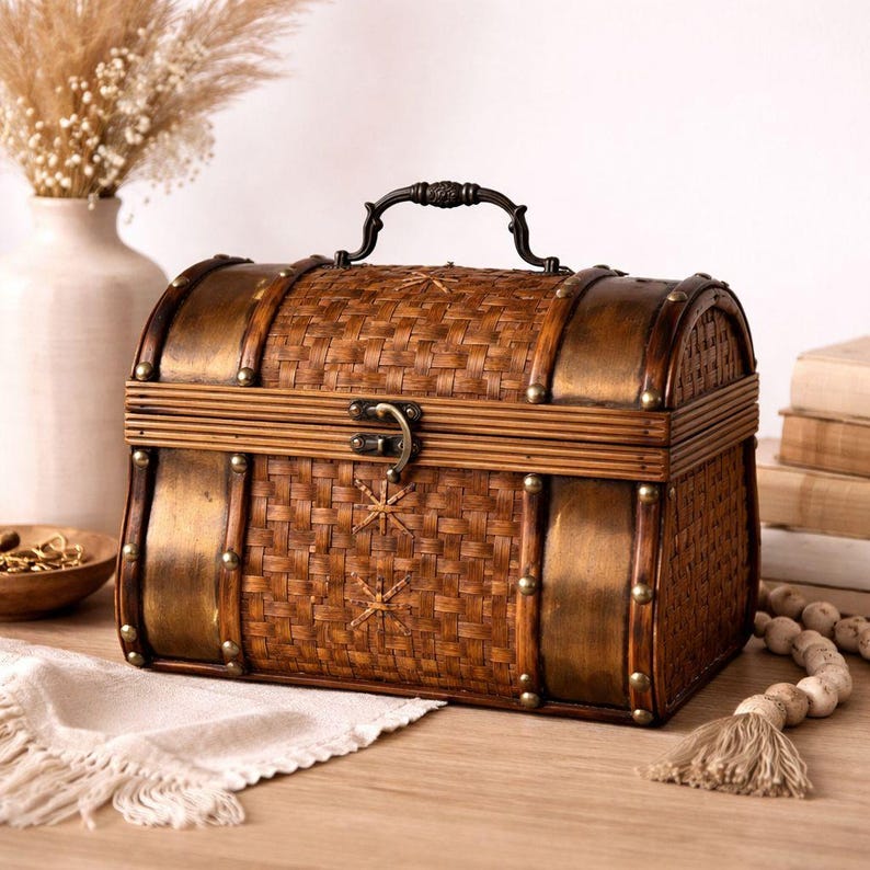 May include: A decorative brown chest with a woven design, metal accents, and a handle. The chest features a curved top and is secured with a latch. The chest is made of wood and metal and has a vintage aesthetic.