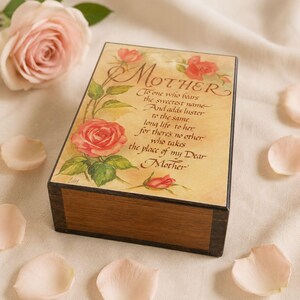 May include: A rectangular wooden keepsake box with a dark brown finish. The lid features a cream-colored panel with illustrations of pink roses and green leaves, inscribed with the text: MOTHER, To one who bears the sweetest name...
