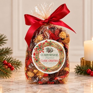 Pode incluir: Um saco de plástico transparente cheio de potpourri vermelho e bege, atado com uma fita de cetim vermelha. Um rótulo circular apresenta uma ilustração de uma coroa e o texto: COUNTRYSIDE Fragrances CLASSIC CHRISTMAS NET WT. 4 OZ./113 G. Contém botânicos.