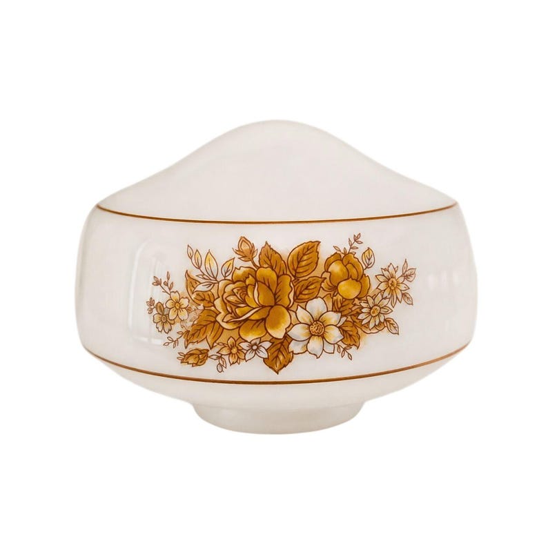 May include: A white ceramic lid with a floral design in shades of gold and brown. The lid has a rounded top and a band of gold trim. The floral pattern includes roses and other flowers.