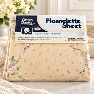 May include: A twin flat flannelette sheet in a cream color with a floral pattern of small pink and blue flowers. The packaging label reads Cotton Comfort Flannelette Sheet, 60% Cotton, 40% Polyester, and 66 x 96 in. finished size.