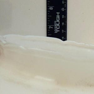 May include: A black ruler with white markings and the text "HYPER TOUGH" is positioned vertically against a white, textured surface. The ruler measures up to 8 inches.