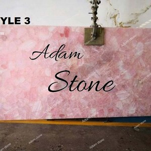 Może przedstawiać: Zbliżenie na różowo-białą płytę kamienną z napisem "Adam Stone" napisanym czarnym, ozdobnym pismem. Płyta jest oznaczona jako "STYLE 3".