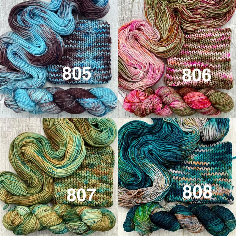 May include: Four sets of hand-dyed yarn skeins and matching knitted swatches labelled 805, 806, 807, and 808. The yarn colours include blue and brown, pink and olive, green and gold, and teal and dark blue, each featuring variegated colour patterns.