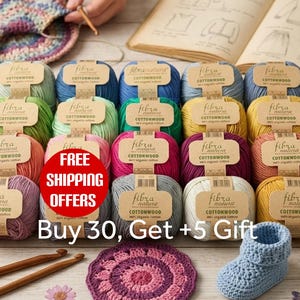 May include: A collection of Fibra Natura Cottonwood yarn balls in various colors, each with a tan paper label. The yarn is 100% organic cotton. The image includes crochet hooks, a crocheted circular mat, and a small blue crocheted baby bootie.