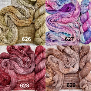 May include: Four skeins of yarn with matching knitted swatches, labelled 626 in tan, 627 in variegated pink and blue, 628 in deep red, and 629 in light brown. Each set displays the yarn texture and colour variation clearly.