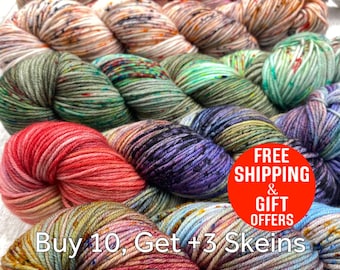 May include: A collection of hand-dyed yarn skeins in various variegated colorways including shades of pink, green, blue, purple, and earth tones. The skeins are arranged in a stacked formation, showcasing the twisted texture of the fiber.