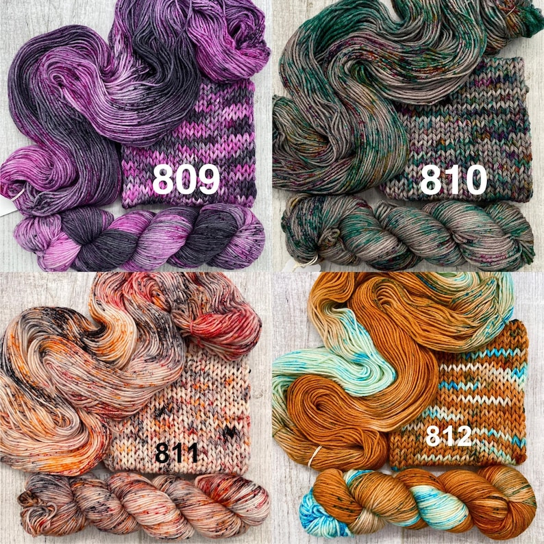 May include: Four skeins of hand-dyed yarn with matching knitted swatches. The yarn colours include purple and black labelled 809, green and brown labelled 810, orange and cream labelled 811, and gold and turquoise labelled 812.