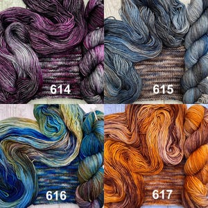 May include: Four skeins of hand-dyed yarn with matching knitted swatches, labelled 614 in purple and black, 615 in blue and grey, 616 in blue and green, and 617 in orange and brown, each displaying unique variegated colour patterns.