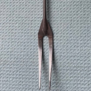 May include: A red handled metal fork with two tines. The fork is designed for grilling and has a long handle.