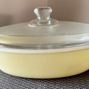May include: A yellow glass baking dish with a clear glass lid. The dish is oval shaped and has a white rim.