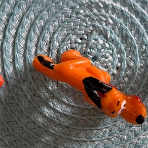 以下が含まれることがあります： ディズニーキャラクターのフィギュア3体：ドナルドダック、プルート、ミッキーマウス。ドナルドダックは青い船乗り帽とジャケットを着ています。プルートはオレンジ色で黒い斑点があります。ミッキーマウスは彼のクラシックな衣装です。