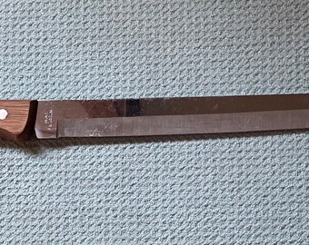 May include: A long, silver kitchen knife with a wooden handle. The handle has three white dots.