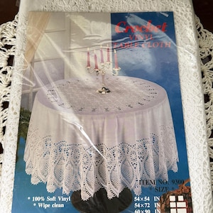 May include: A white vinyl tablecloth with a crochet-style pattern, packaged in plastic. The packaging features the text Crochet Vinyl Tablecloth, Item No. 9300, and lists sizes including 54x54 in, 54x72 in, 60x90 in, 60x104 in, and 70 in round.