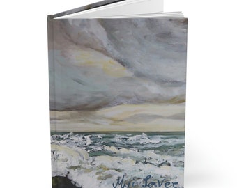 Puede incluir: Un diario de tapa dura con una pintura de un mar tormentoso con olas blancas y un cielo nublado. La firma del artista, "Mari LaVer", está en la esquina inferior derecha.