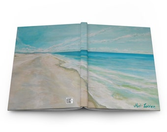 May include: An open book with a painting of a beach scene. The painting depicts a sandy beach with turquoise water and white clouds in a light blue sky. The book is signed "Miri Laver" on the right page.