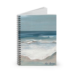 Könnte beinhalten: Ein spiralgebundenes Notizbuch mit einem blauen und weißen Meereslandschaftsgemälde auf dem Cover. Das Gemälde zeigt ein blaues Meer mit weißen Wellen, die an einem Sandstrand brechen. Die Unterschrift des Künstlers, "Miri Lawee", befindet sich in der rechten unteren Ecke des Gemäldes.