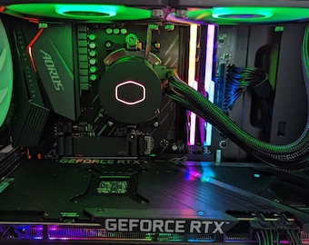 May include: A black computer case with a green and purple RGB lighting system. The case has a clear side panel that shows the internal components, including a black motherboard with a CPU cooler, a black graphics card with the text "GEFORCE RTX" on it, and several black RAM sticks with RGB lighting.