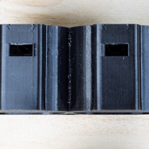 K&ouml;nnte beinhalten: Zwei schwarze Kunststoffstecker mit rechteckigen &Ouml;ffnungen.