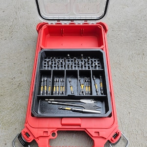 May include: Red plastic tool box with a clear lid, open to reveal a black tray with a variety of drill bits and screwdriver bits. The tray has a grid pattern to organise the bits.