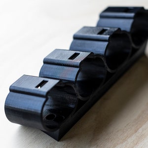 K&ouml;nnte beinhalten: Ein schwarzer Batteriehalter aus Kunststoff mit vier Steckpl&auml;tzen f&uuml;r Batterien.