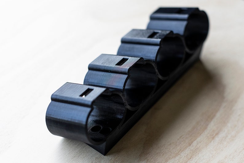 K&ouml;nnte beinhalten: Ein schwarzer Batteriehalter aus Kunststoff mit vier Steckpl&auml;tzen f&uuml;r Batterien.