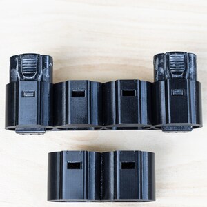 K&ouml;nnte beinhalten: Schwarzer Batteriehalter aus Kunststoff mit sechs Steckpl&auml;tzen f&uuml;r Batterien. Der Halter ist in zwei Abschnitte unterteilt, einen mit zwei Steckpl&auml;tzen und den anderen mit vier Steckpl&auml;tzen.