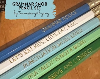 Può includere: Un set di cinque matite con legno di diversi colori e lettere dorate. Le matite sono etichettate "Grammar Police", "Let's Eat Kids. Let's Eat, Kids.", "Punctuation Saves Lives!", "PSA: 'Alot' Is Not A Word", and "To Serve And Correct".
