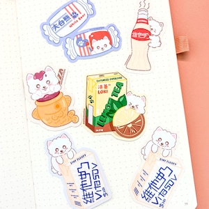 May include: A collection of colorful stickers featuring cartoon bears and food items. Designs include candy, a bottle of milk, a fish-shaped pastry, a tea box, and a lemon slice. Text includes "White Bear", "Cuteness Overload", and "Stay Floofy".