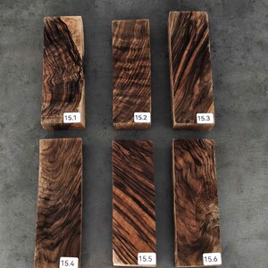 May include: Six rectangular wooden blocks with distinct dark brown and tan grain patterns. Each block features a white label with black text: 15.1, 15.2, 15.3, 15.4, 15.5, and 15.6. The wood surfaces show natural, swirling, and linear textures.