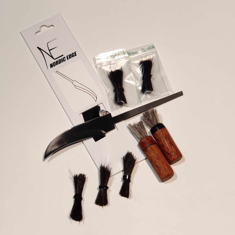 K&ouml;nnte beinhalten: Ein Set aus vier schwarzen und braunen B&uuml;rsten mit Holzgriffen, verpackt mit einem schwarzen Messer und einer wei&szlig;en Karte mit dem Text "NE NORDIC EDGE".