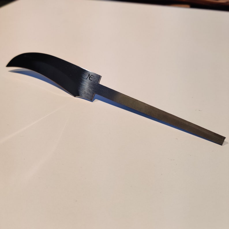 K&ouml;nnte beinhalten: Eine silberne Messerklinge mit einer gebogenen Kante und einem geraden Griff. Die Klinge tr&auml;gt eine kleine Inschrift mit der Aufschrift "NE".