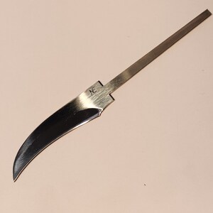 K&ouml;nnte beinhalten: Eine silberne Messerklinge mit einer gebogenen Kante und einem geraden R&uuml;cken. Die Klinge ist mit dem Buchstaben "X" gekennzeichnet.