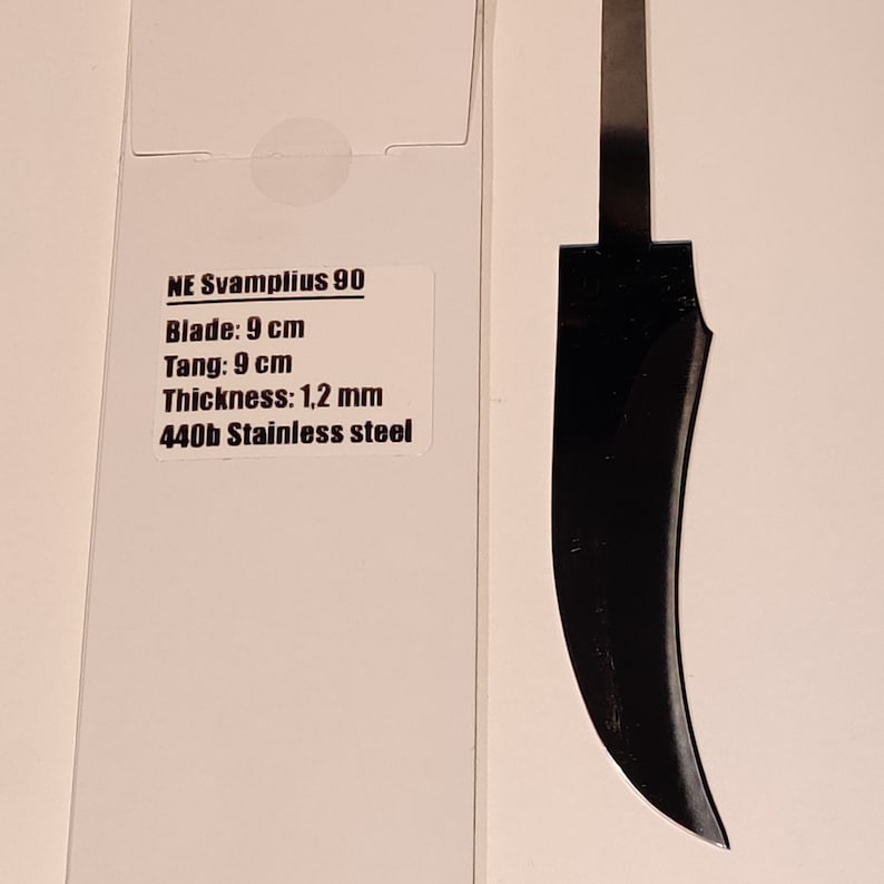 K&ouml;nnte beinhalten: Eine schwarze Messerklinge mit einer gebogenen Kante. Die Klinge ist 9 cm lang und 1,2 mm dick. Die Klinge ist aus 440b Edelstahl.