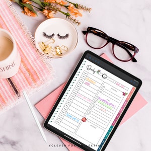 May include: An iPad showing a digital daily planner with a floral design. The planner includes a schedule with times and tasks like "Meditation" and "Drinks with sis." Other items include a white stylus, glasses, and a decorative dish with eyelashes.